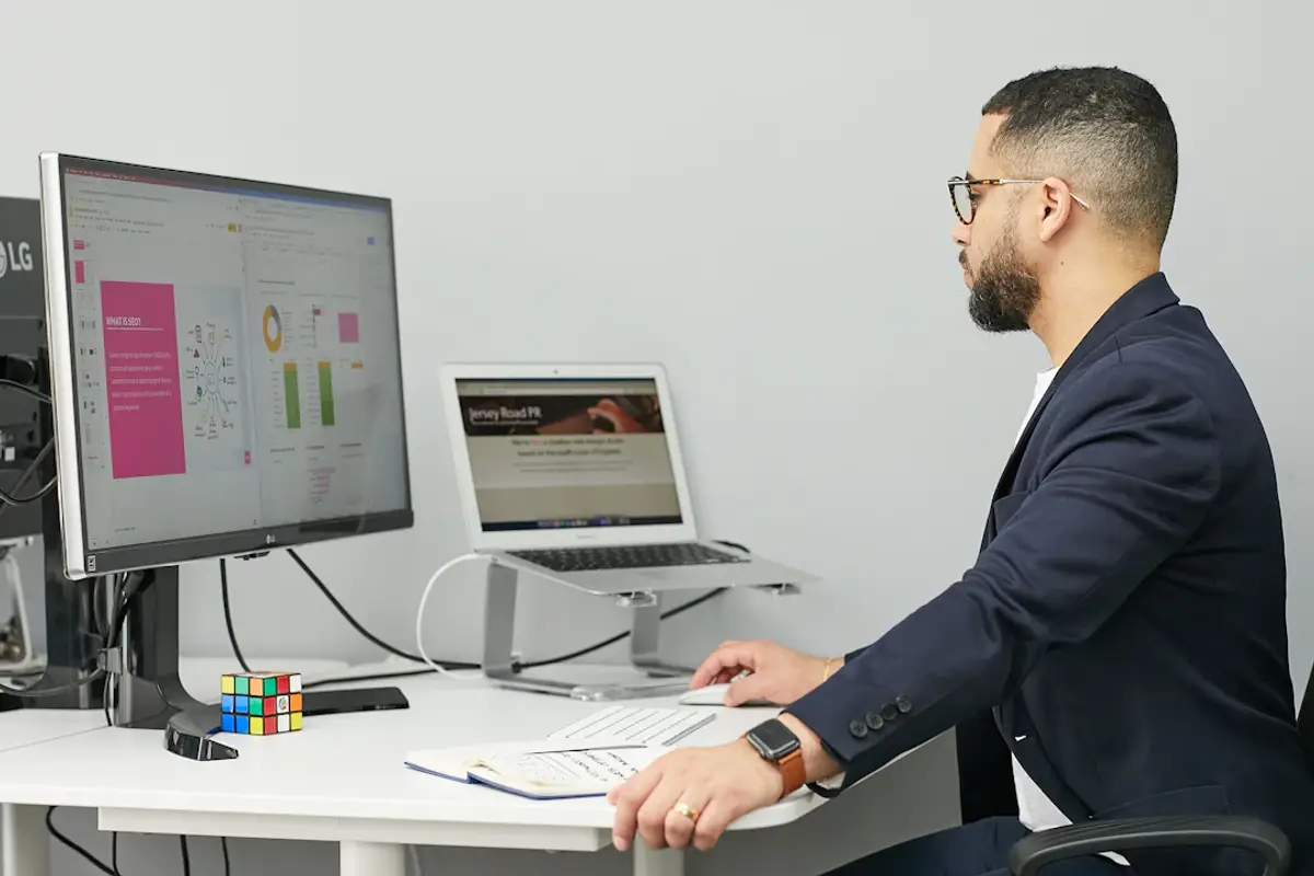 Man in overalls and glasses working at a computer desk